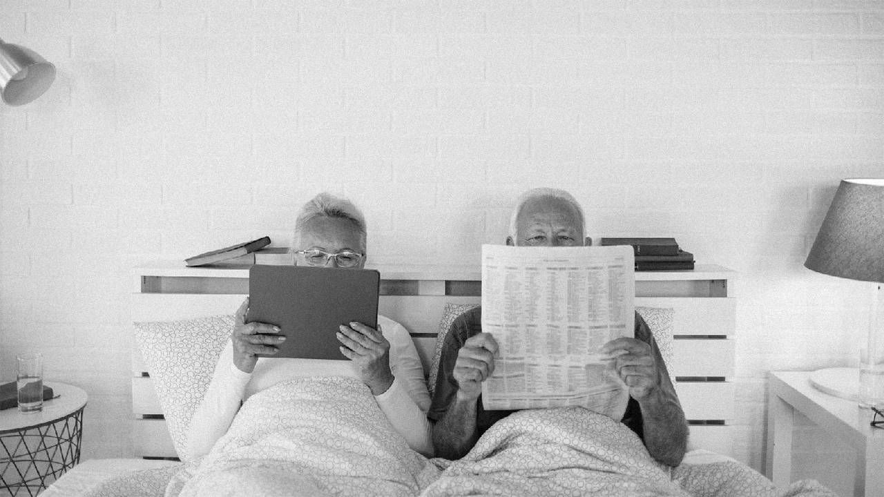 An older couple in bed reading the newspaper. Next Avenue, losing libido aging, low libido