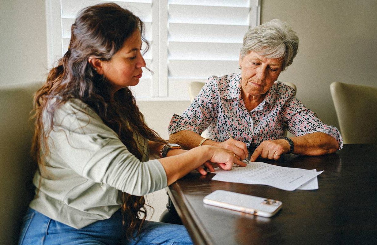 An older adult looking at documents with their adult child. Next Avenue, medicaid estate claims