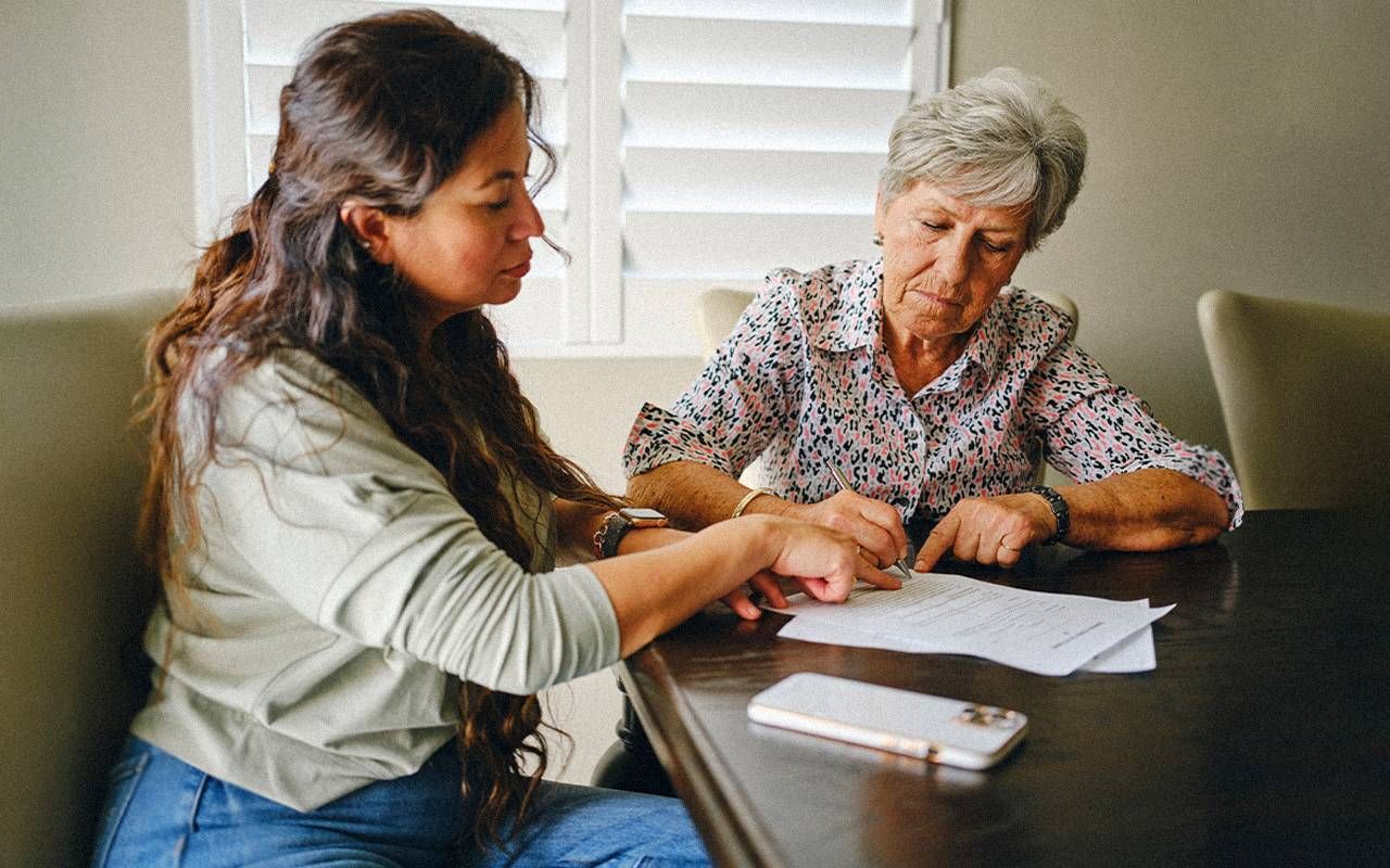 An older adult looking at documents with their adult child. Next Avenue, medicaid estate claims