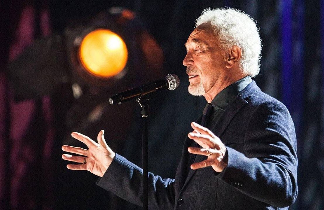 Singer Tom Jones wearing a suit while singing on stage. Next Avenue, music and memory