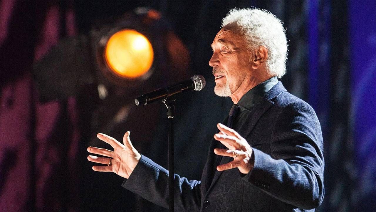 Singer Tom Jones wearing a suit while singing on stage. Next Avenue, music and memory