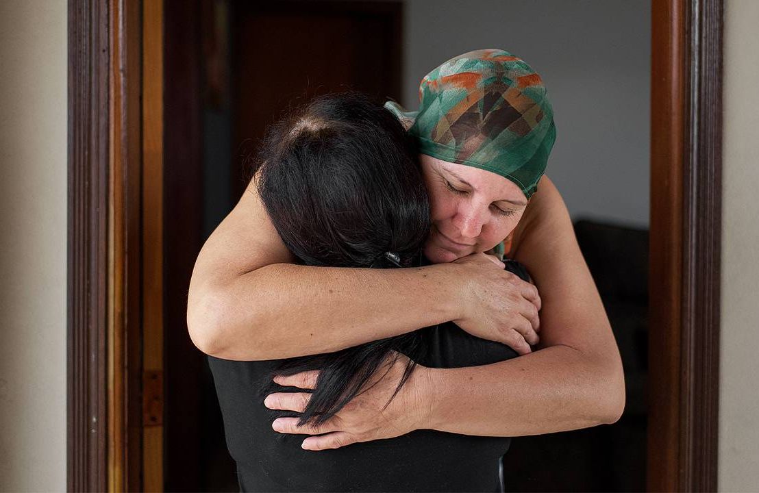A woman with cancer hugs her friend and caregiver. Next Avenue, becoming caregiver for a friend