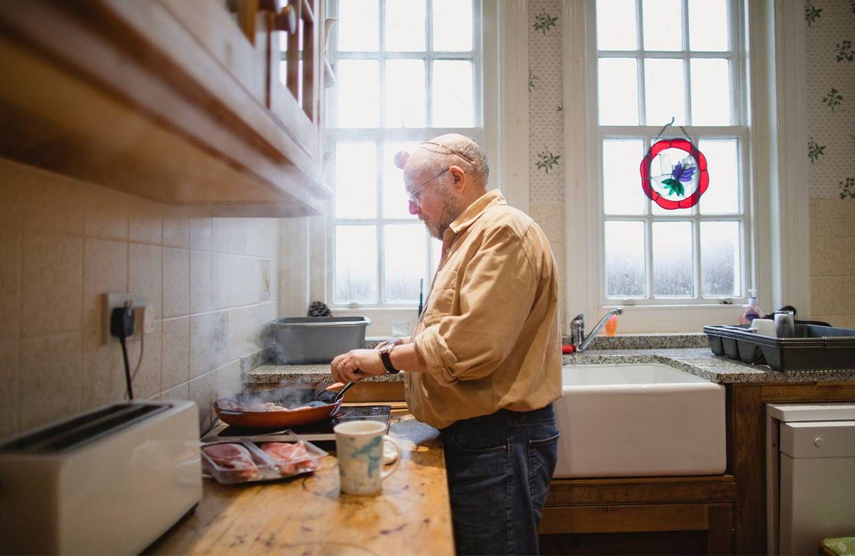 A man cooking alone in his kitchen at home. Next Avenue, loneliness after death of spouse