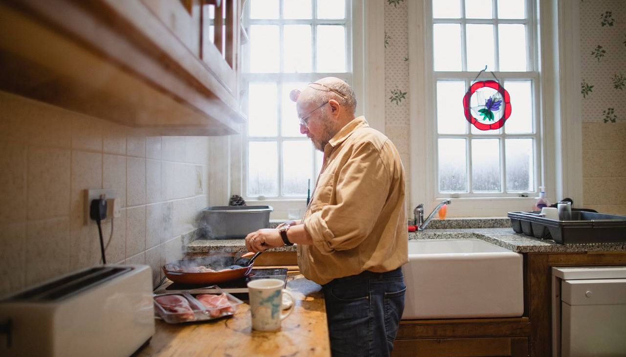 A man cooking alone in his kitchen at home. Next Avenue, loneliness after death of spouse