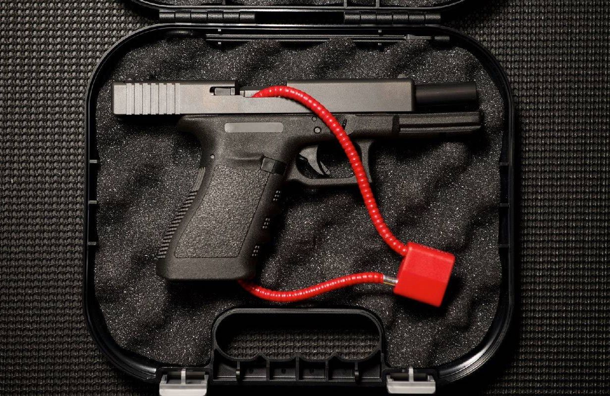 A gun with a red lock placed in a carrying case. Next Avenue, gun safety, safe gun storage