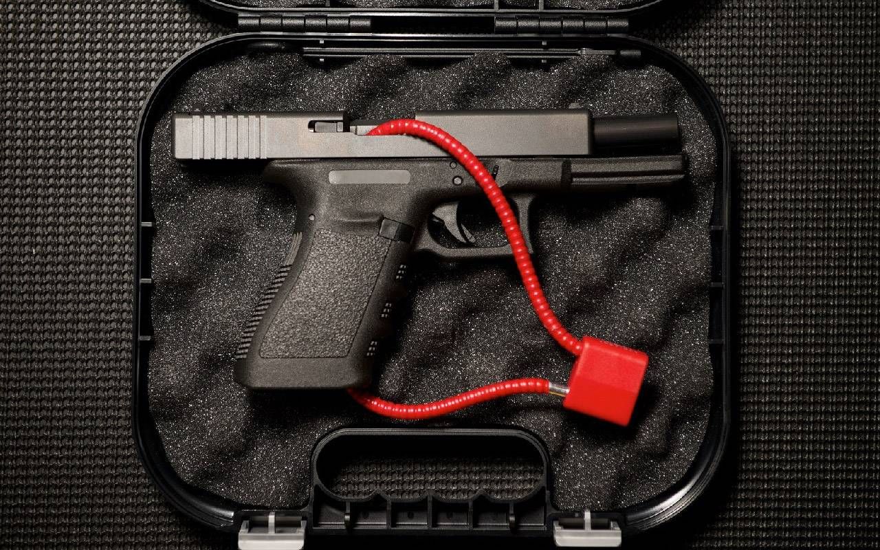 A gun with a red lock placed in a carrying case. Next Avenue, gun safety, safe gun storage