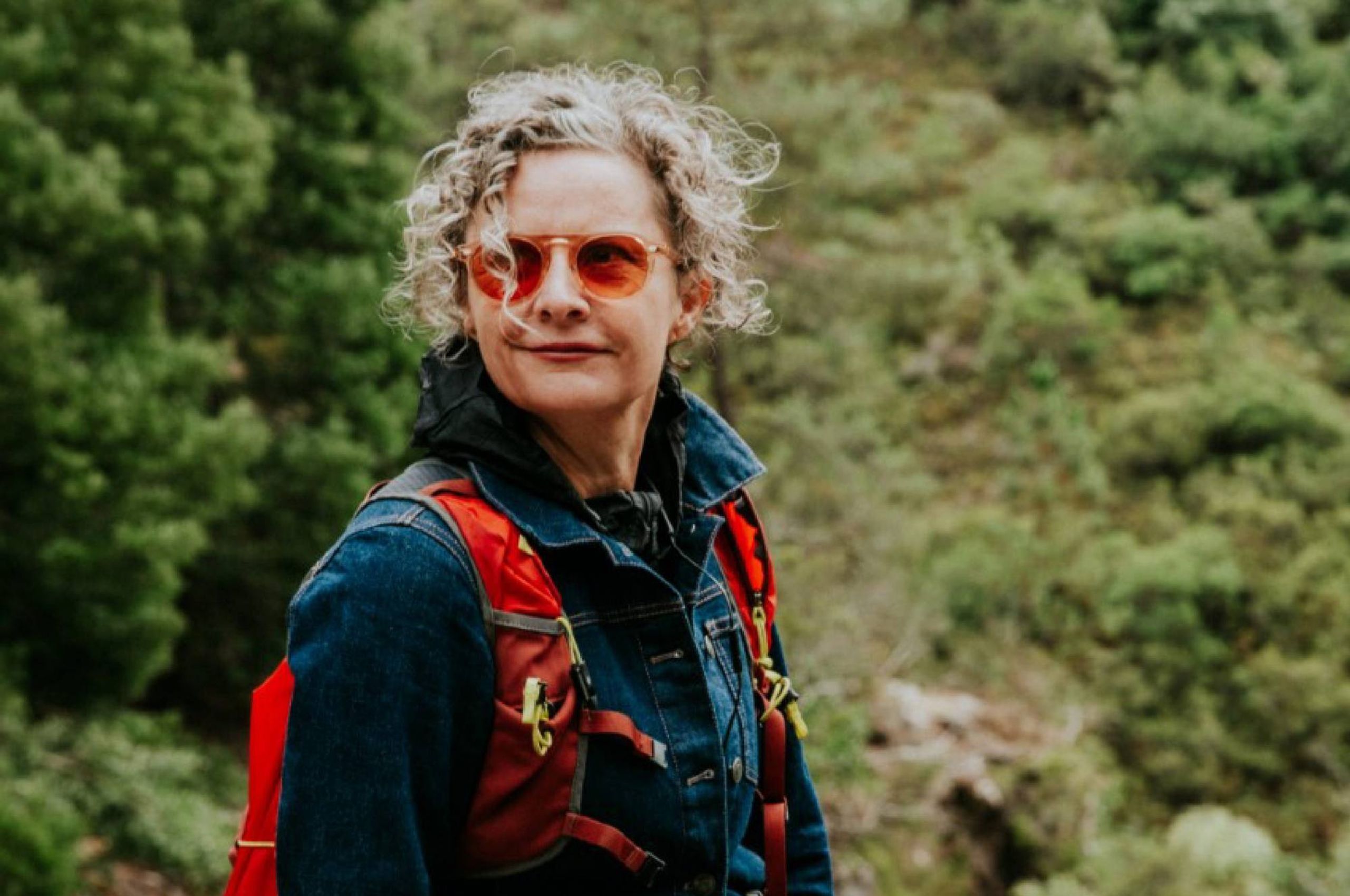 A woman wearing a backpack while hiking in a forest. Next Avenue, Early Majority, Joy Howard