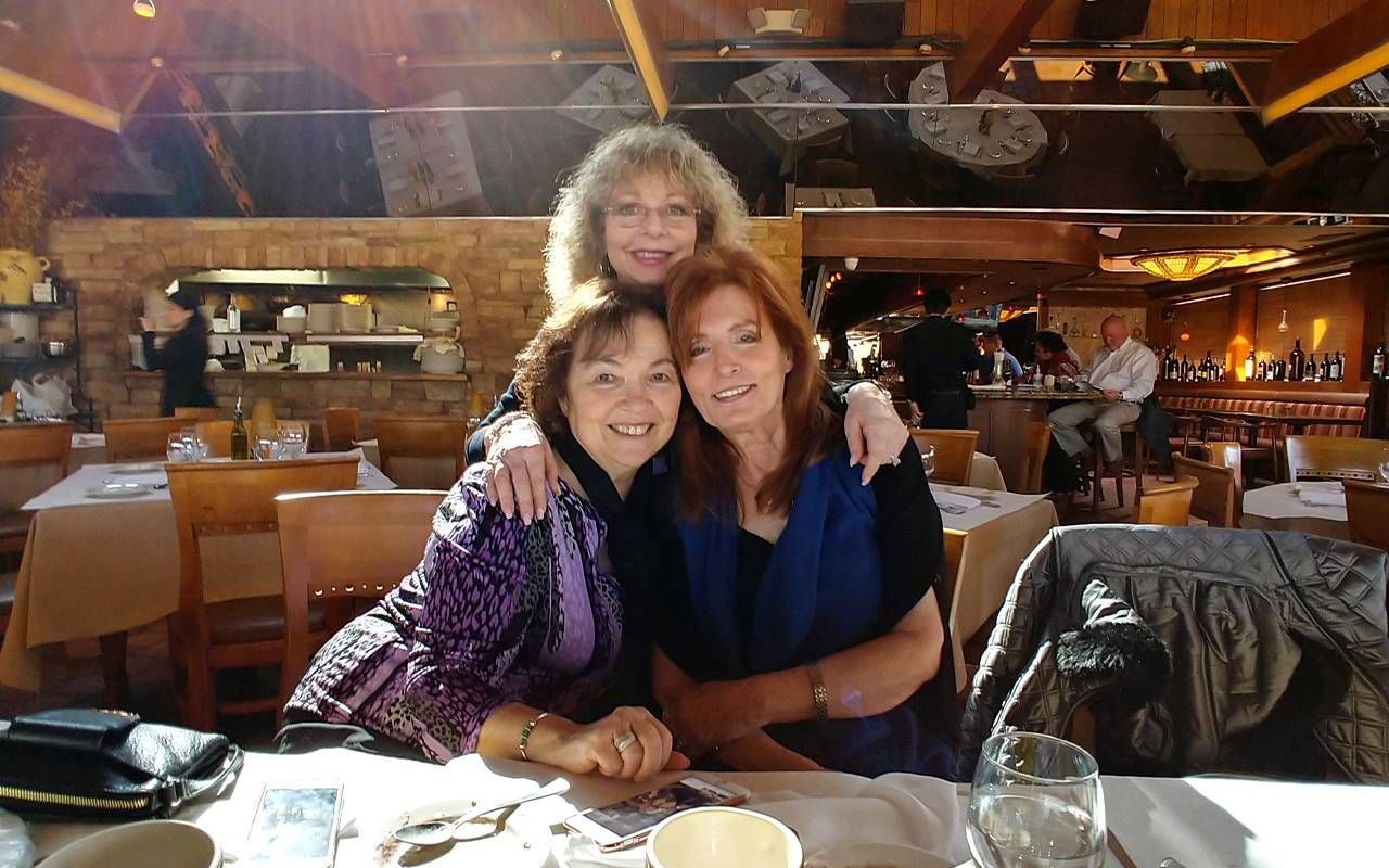 Three women with their arms wrapped around each other at a restaurant. Next Avenue, Friendship group dynamics, long lasting friendships