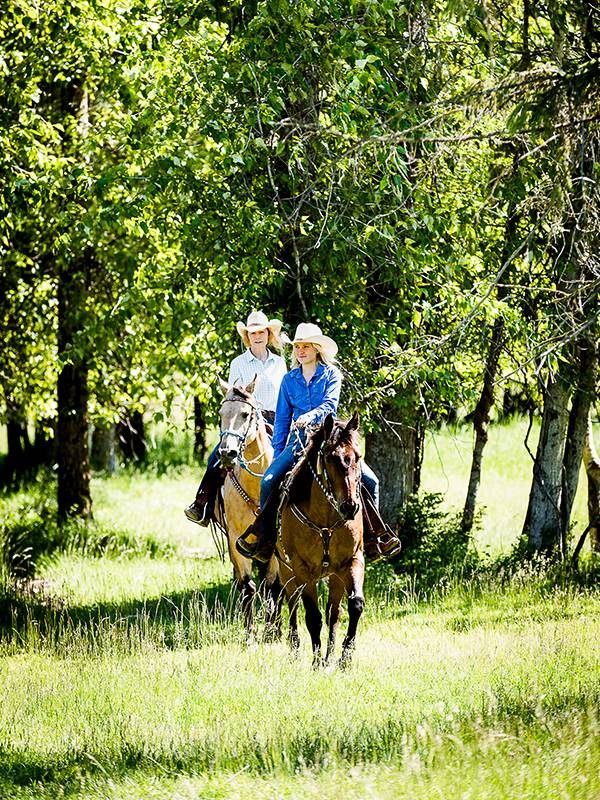 Two people riding horseback in the woods. Next Avenue,