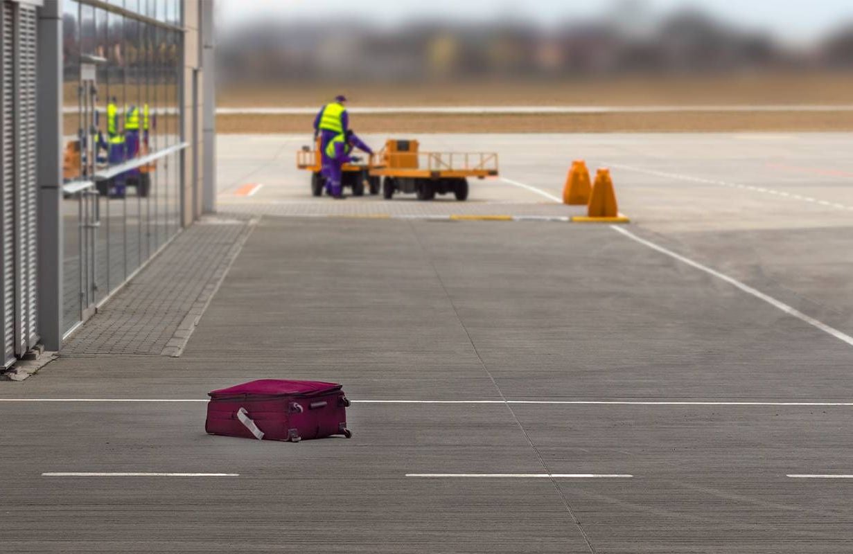 A red piece of luggage left behind on the tarmac. Next Avenue, lost luggage, loosing luggage