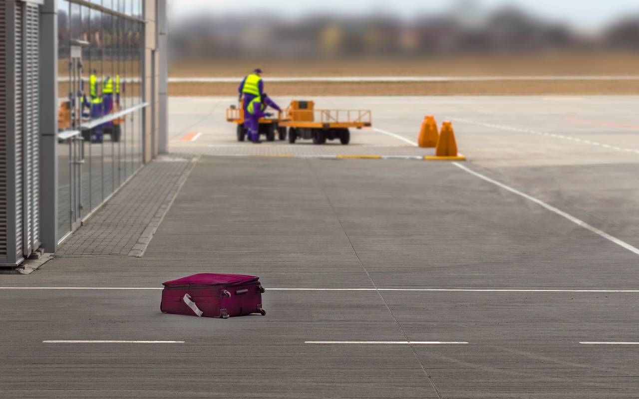 A red piece of luggage left behind on the tarmac. Next Avenue, lost luggage, loosing luggage