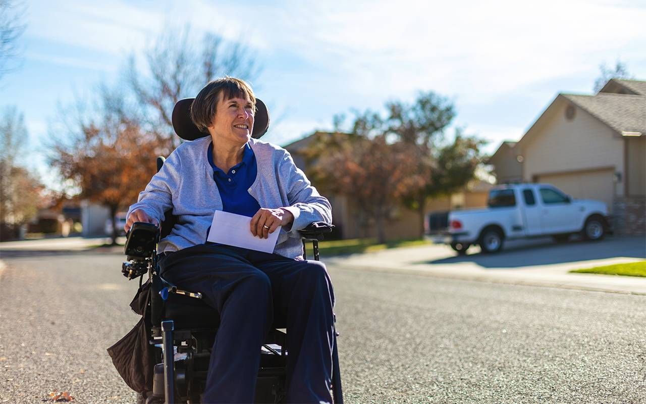 A woman with a disability going down the street to get her mail. Next Avenue