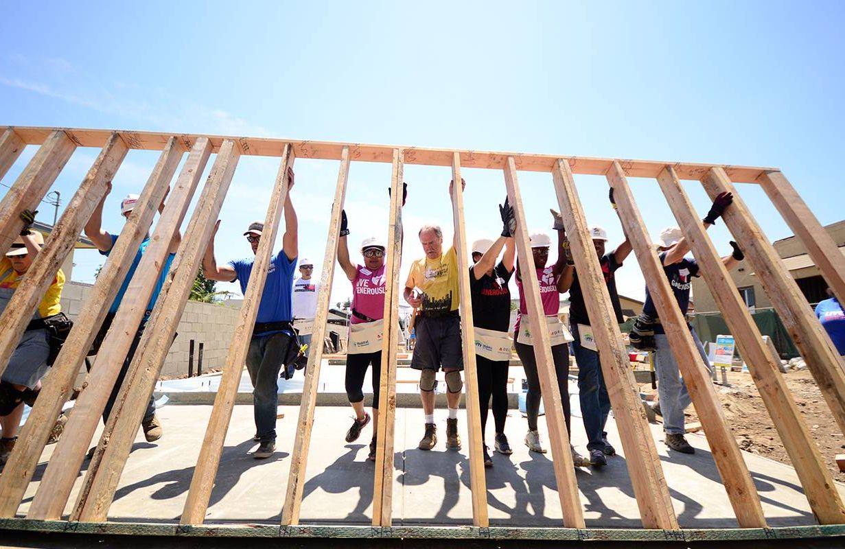 A group of volunteers putting up the framing for a house. Next Avenue,