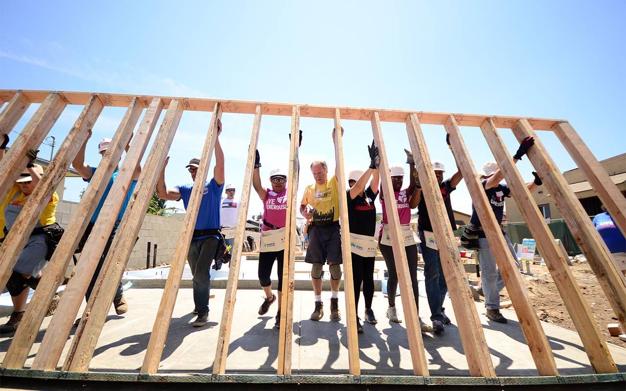 A group of volunteers putting up the framing for a house. Next Avenue,