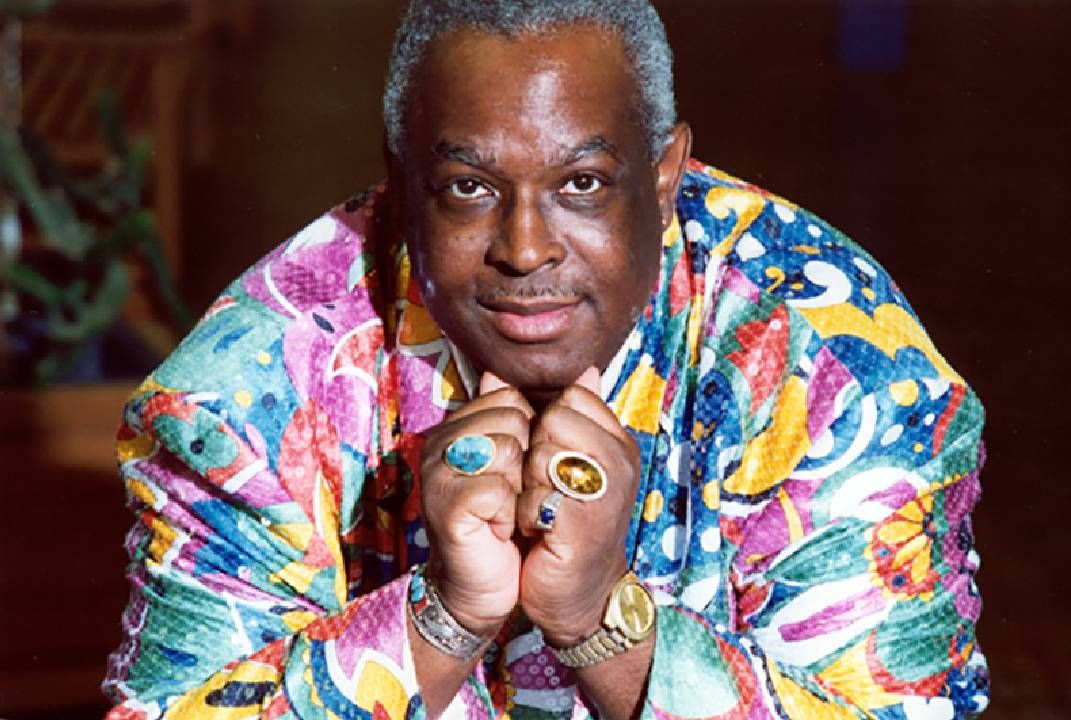 A man wearing a colorful jacket and jewelry. Next Avenue, mr. roger's neighborhood officer clemmons
