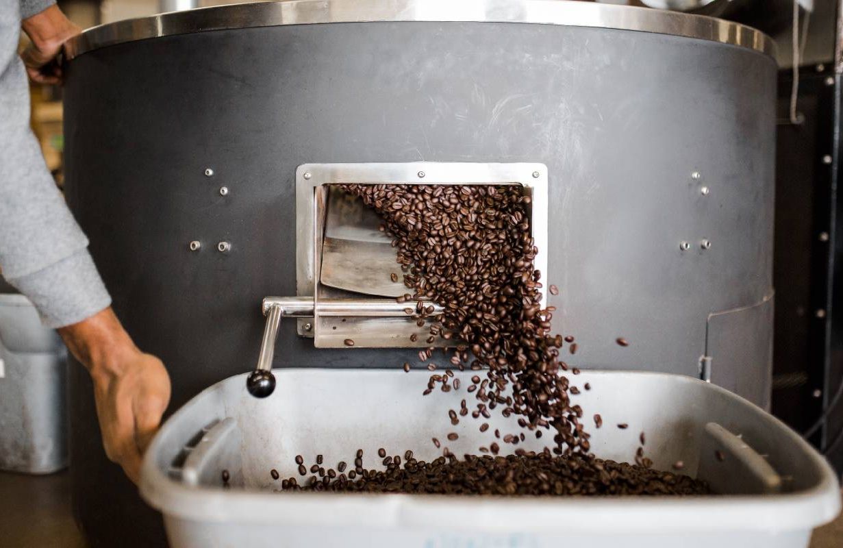 Coffee beans coming out of a coffee bean roaster. Next Avenue, benefits of coffee, coffee vitamins