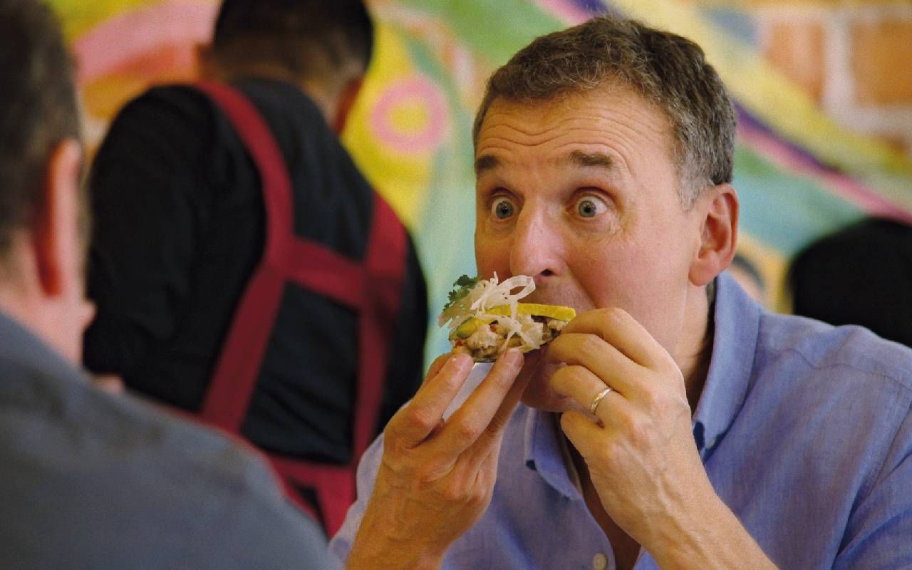 A man looking surprised as he eats a taco. Next Avenue, phil Rosenthal, somebody feed phil