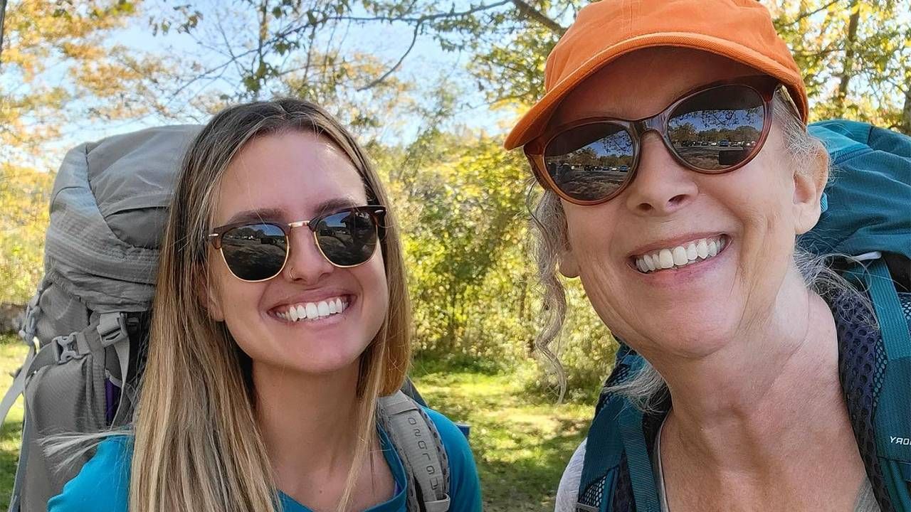 A woman and her daughter smiling while hiking on a trail. Next Avenue, how to start backpacking, older adults