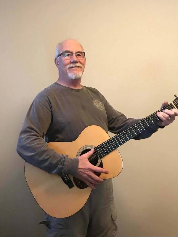 A man holding playing a guitar. Next Avenue