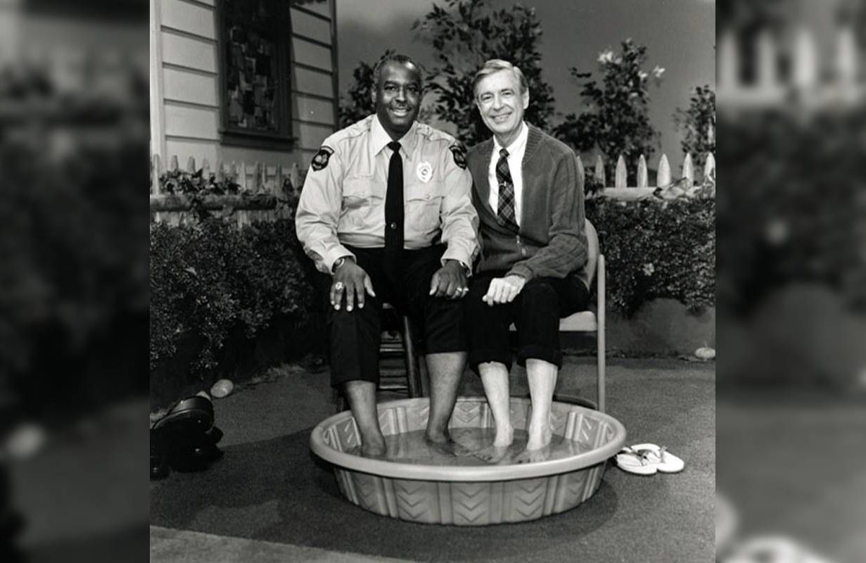 Officer Clemmons and Mr. Rogers putting their feet in a small pool. Next Avenue, mr. roger's neighborhood officer clemmons