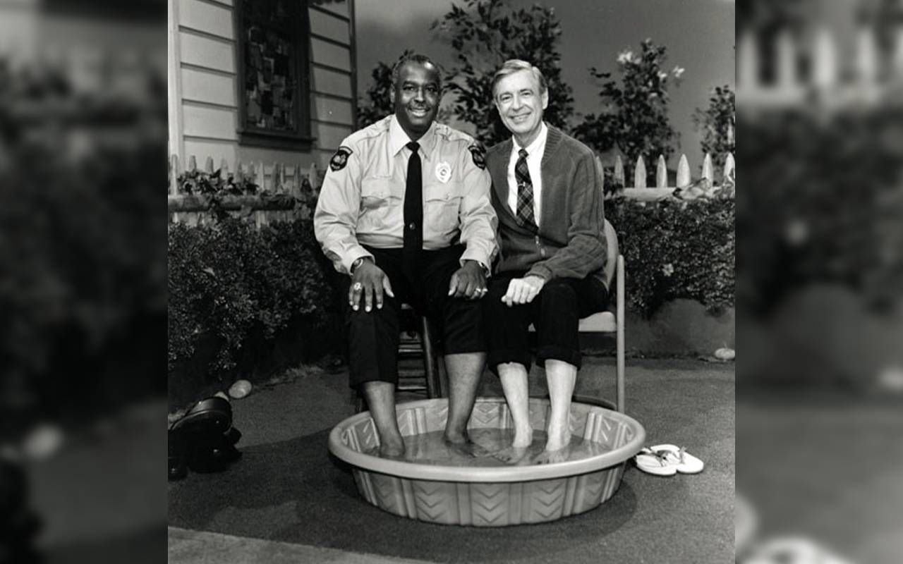Officer Clemmons and Mr. Rogers putting their feet in a small pool. Next Avenue, mr. roger's neighborhood officer clemmons
