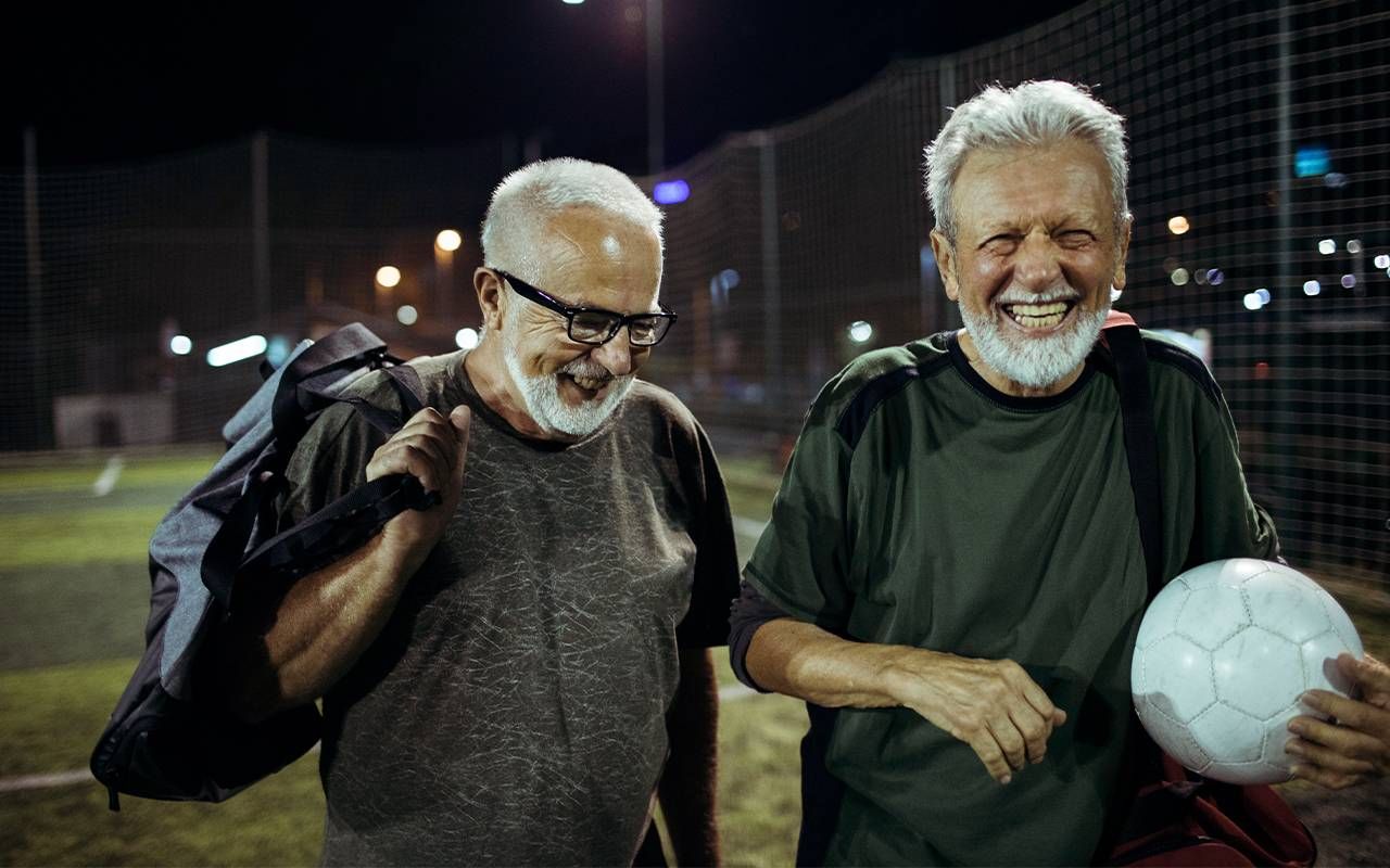 Two friends walking off the field after playing a game of soccer. Next Avenue, exercise, reduce dementia