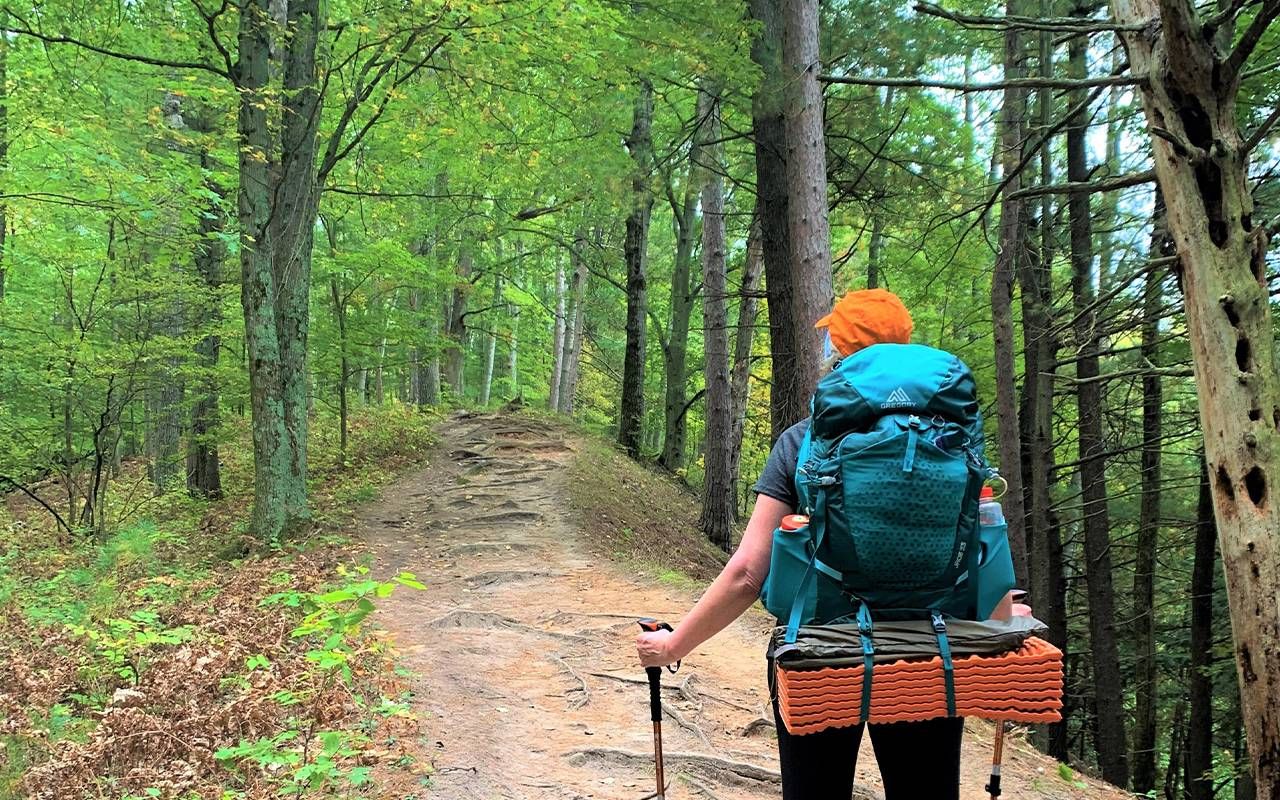 A woman wearing a backpacking backpack while hiking. Next Avenue, how to start backpacking, older adults