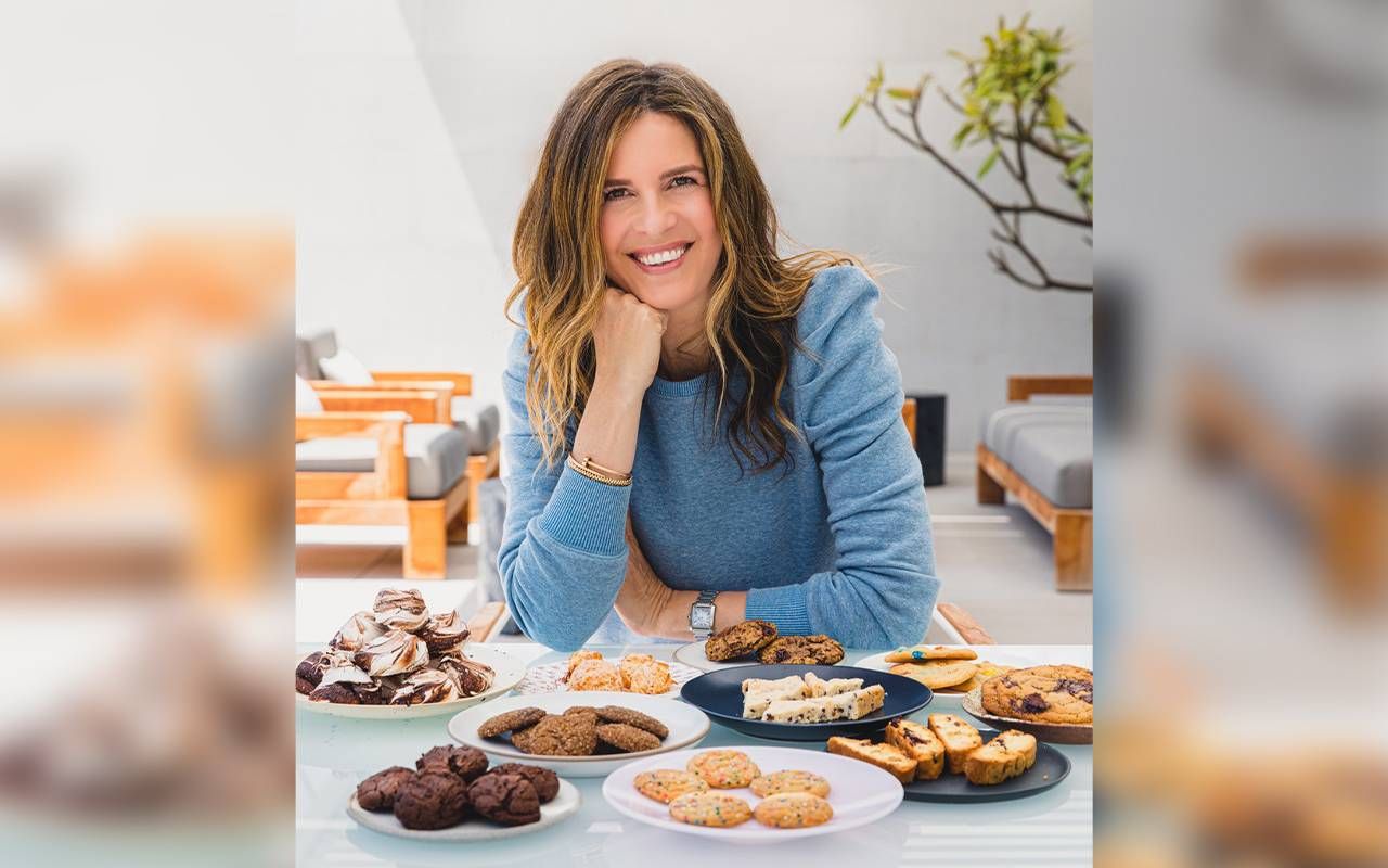 A woman smiling in front of plates of baked goods. Next Avenue, older entrepreneur, sweet success, Candace Nelson book