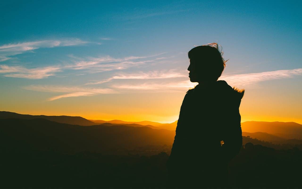 A silhouette of a person looking at the sunset. Next Avenue, talking about death, mortality