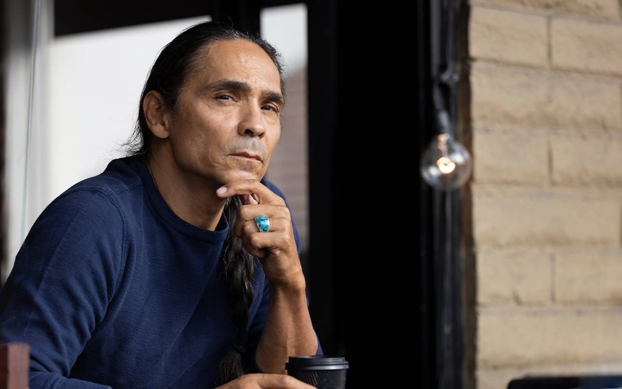 A man sitting and holding a cup of coffee. Next Avenue, Longmire, Reservation Dogs, Zahn McClarnon