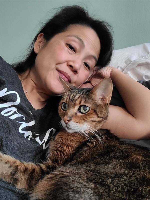 A woman sitting with her cat on a couch. Next Avenue, losing a pet, grieving a pet
