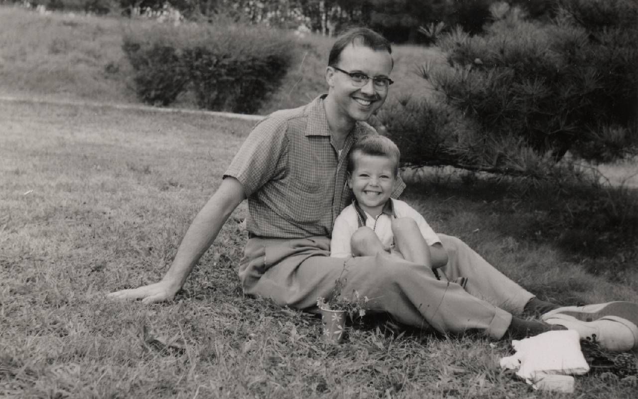 A father sitting with his young son in the grass. Next Avenue, Ken Burns, Our America