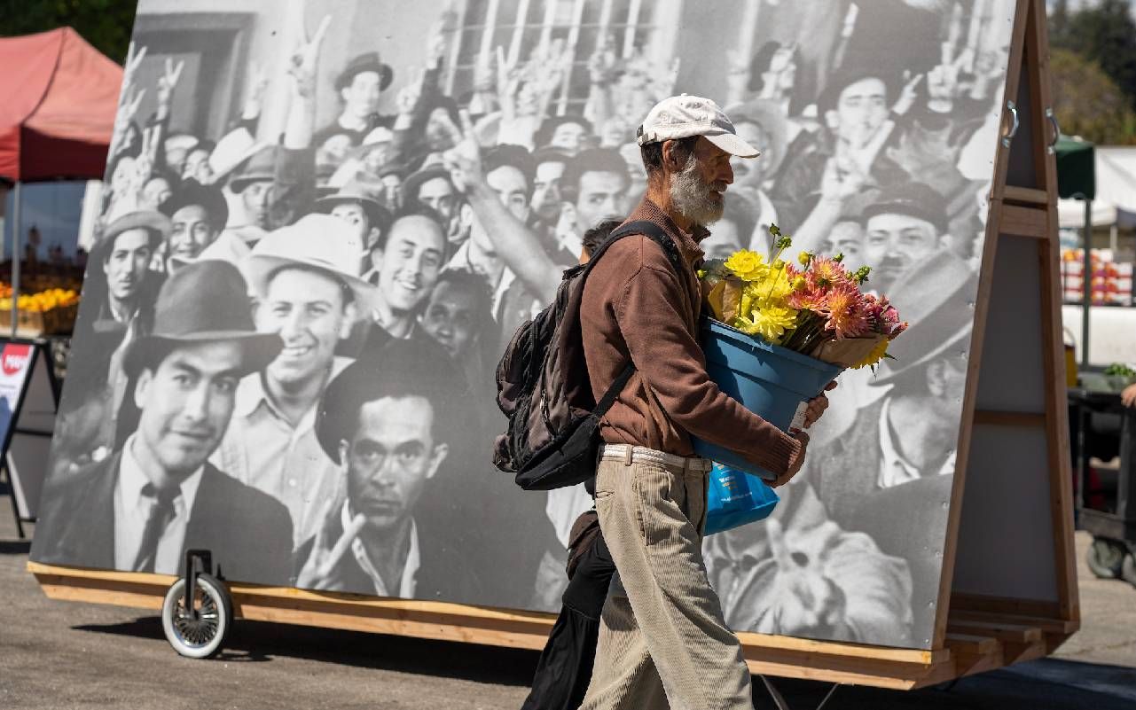 A man walking with a bucket of flowers. Next Avenue, Santa Cruz Museum of Art and History