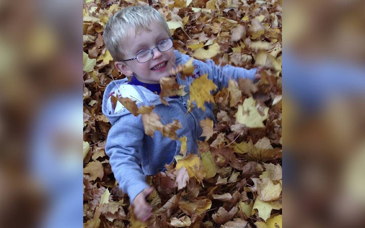 A young boy playing in a pile of leaves. Next Avenue
