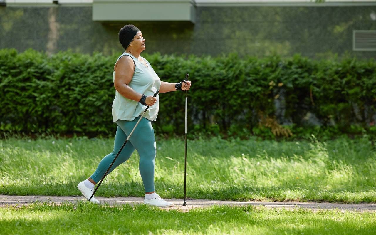 A woman exercising by walking outside. Next Avenue