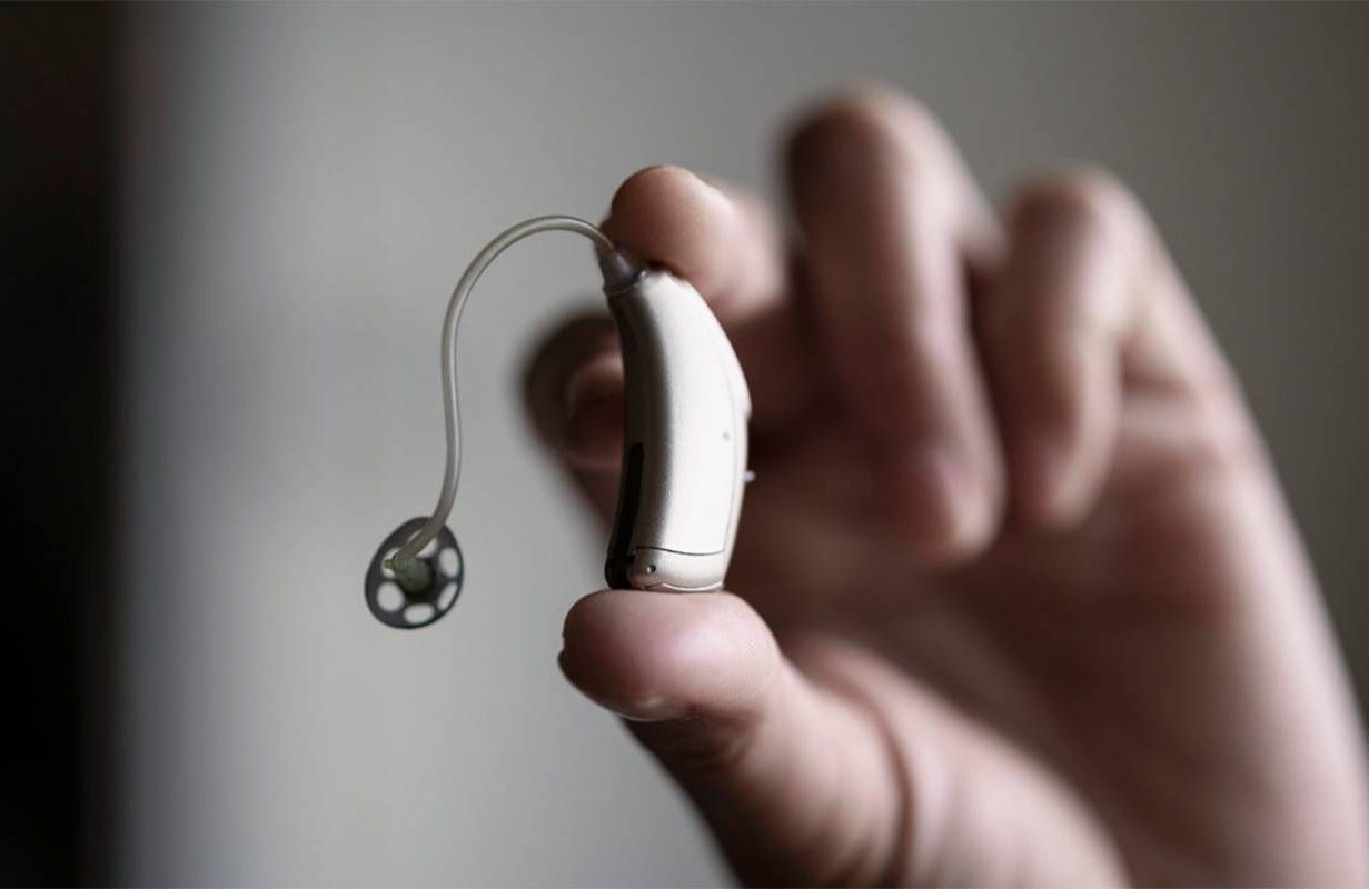 A person holding up a new hearing aid. Next Avenue, over the counter hearing aid, OTC