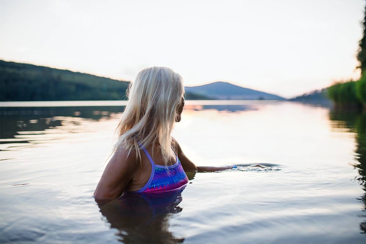 A woman swimming in a lake. Next Avenue, decluttering your life