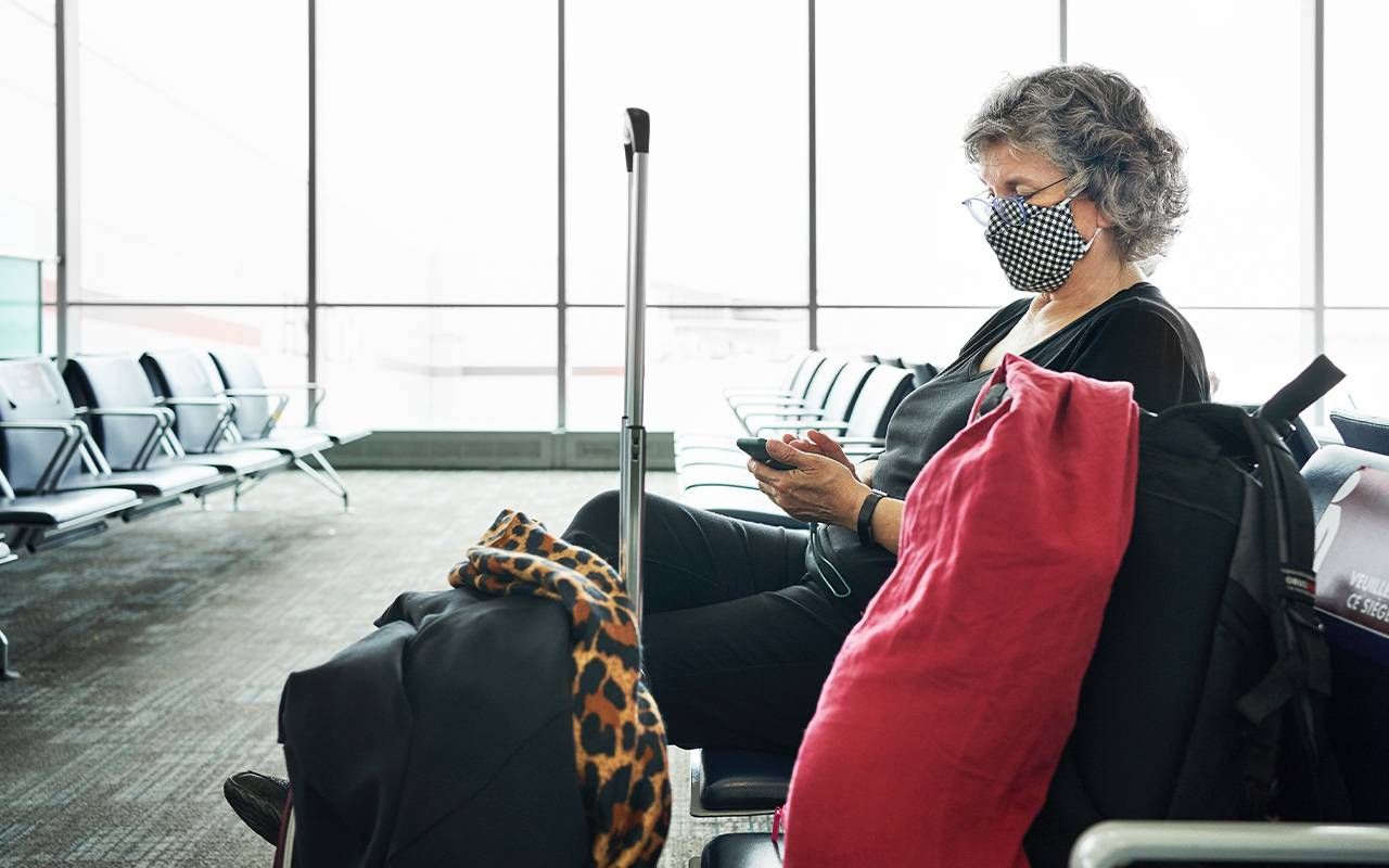 A person sitting in an airport on their cell phone. Next Avenue