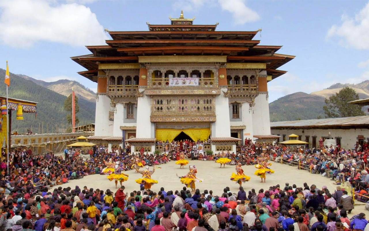 A monastery with a large crowd gathered in the courtyard. Next Avenue, travel, Bhutan, black-neck crane festival,