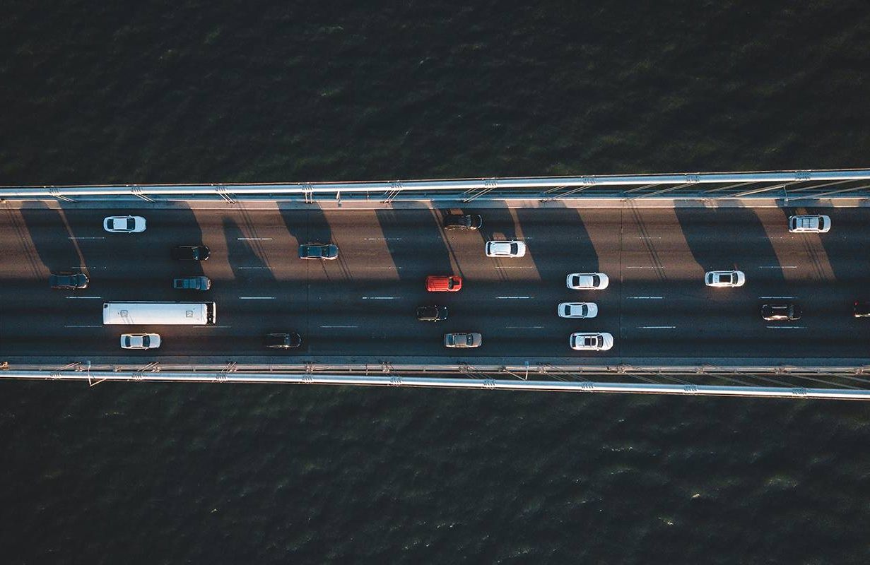 An aerial view of cars driving on a bridge. Next Avenue, pay for car insurance