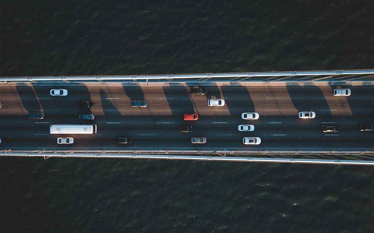 An aerial view of cars driving on a bridge. Next Avenue, pay for car insurance
