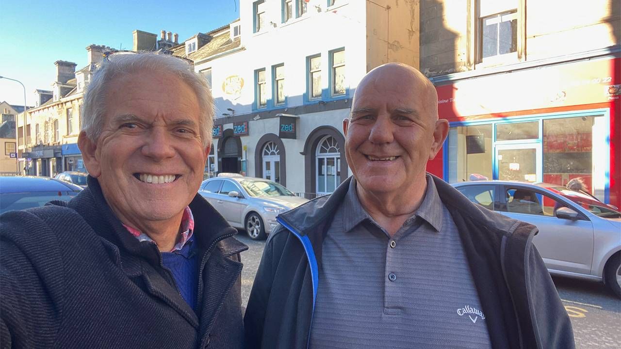 Two men smiling on a street. Next Avenue, visiting ancestral land, family genealogy, family history