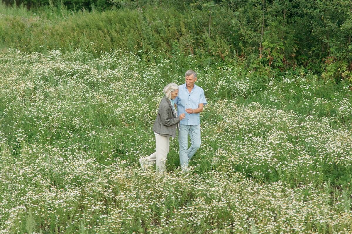 A couple walking in a field of flowers. Next Avenue, romance at midlife.