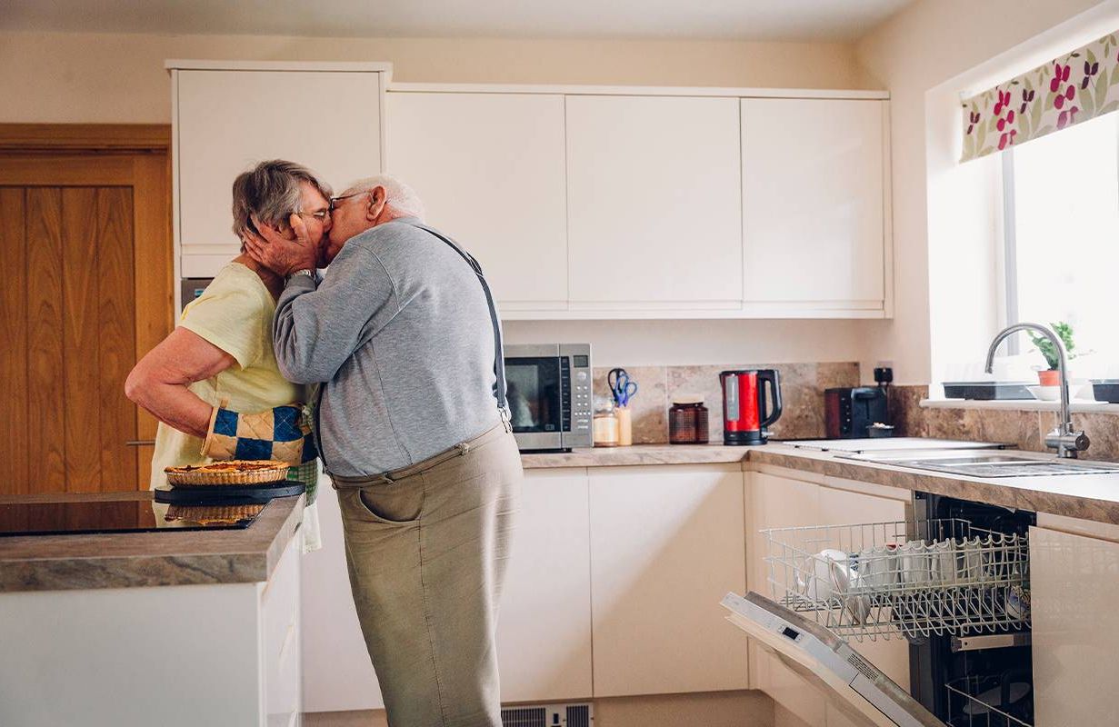 An older couple kissing in the kitchen. Next Avenue, sexual ageism, sex in your 60s, midlife