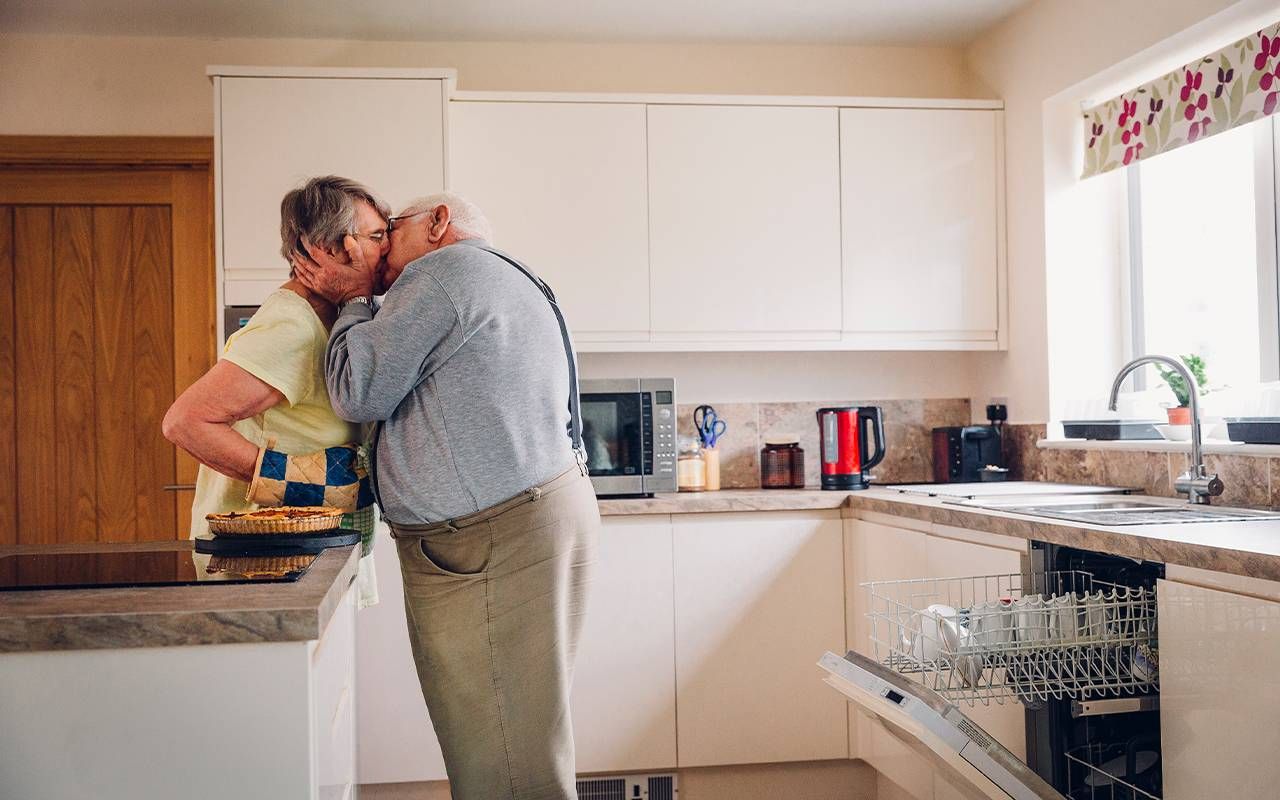 An older couple kissing in the kitchen. Next Avenue, sexual ageism, sex in your 60s, midlife