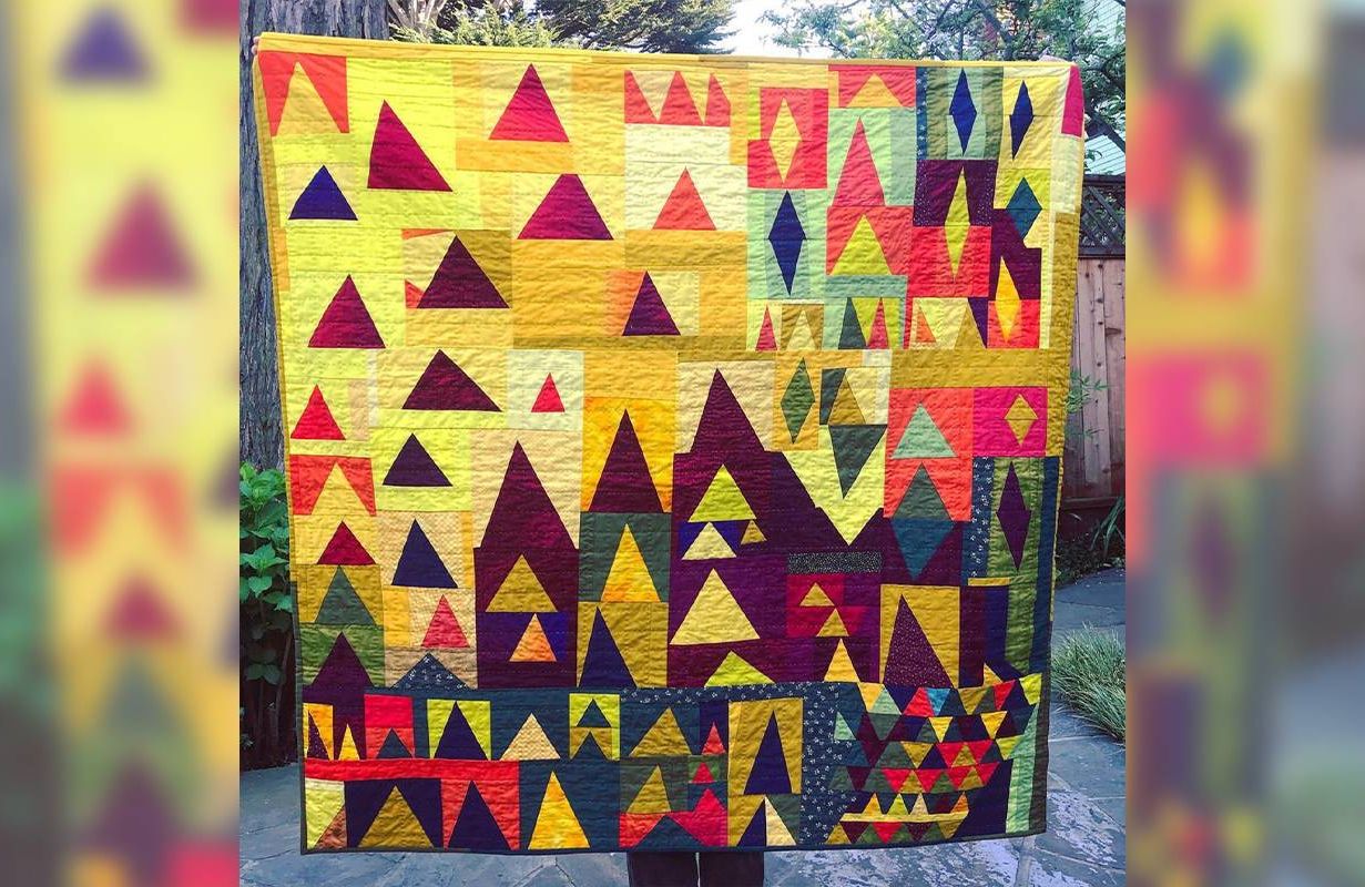 A person holding up a colorful quilt. Next Avenue, quilting, creative aging