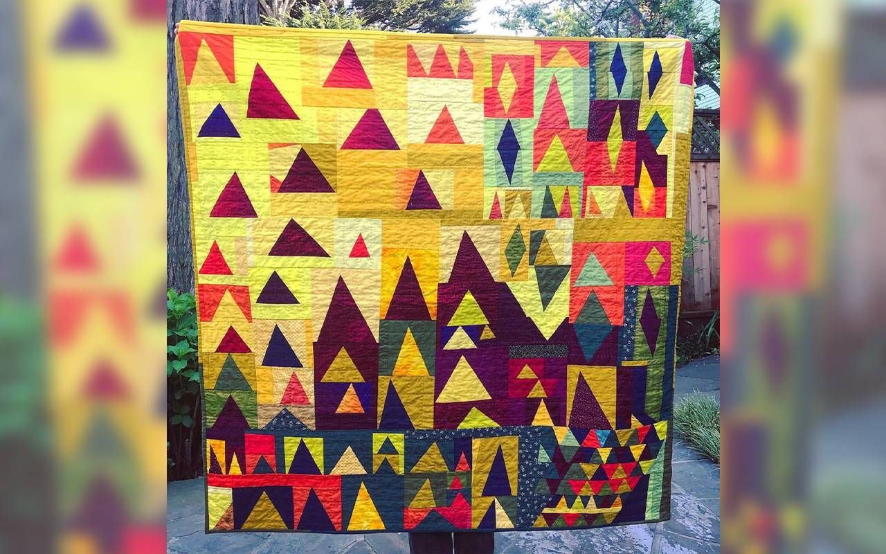 A person holding up a colorful quilt. Next Avenue, quilting, creative aging