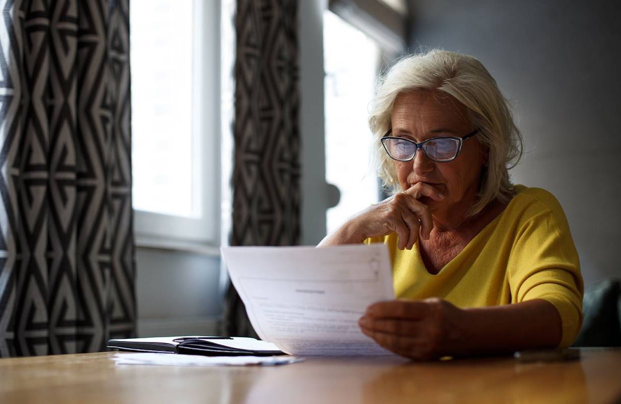 An older woman looking at her finances. Next Avenue, retirement gender gap
