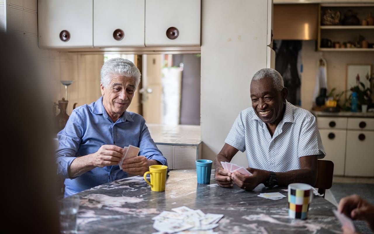 older adults playing cards at a table. Next Avenue, CCRC