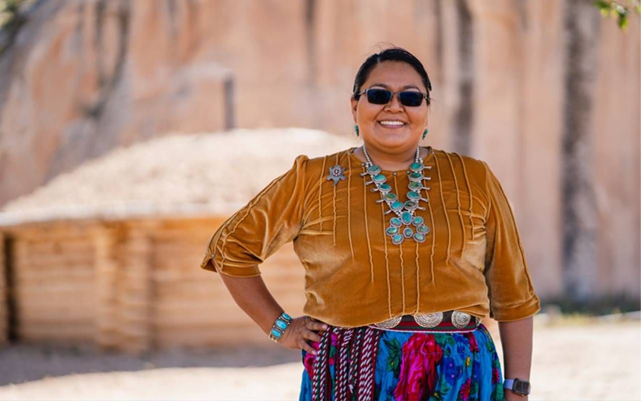 A woman wearing colorful clothing smiling outside. Next Avenue, Navajo Caregivers